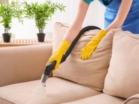 Woman cleaning couch with vacuum cleaner at home