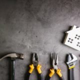 Wooden house and construction tools on stone pattern background with copy space.Home Repair concept, Repair maintenance concept, Renovation concept.