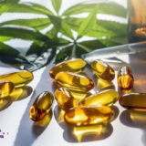 Medical cannabis products: leaf, capsules and CBD oil on white b