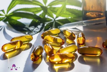 Medical cannabis products: leaf, capsules and CBD oil on white b