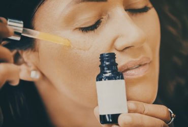 Close up of mid adult woman applying face serum on her face.