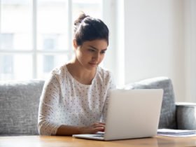 Focused Indian woman using laptop at home, looking at screen